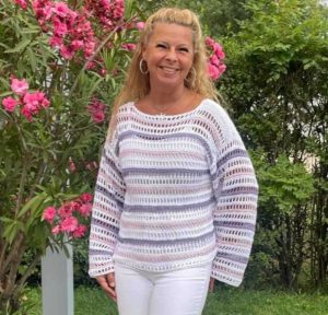 Claudia Hess fröhlich lachend vor einem Oleanderstrauch