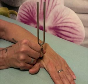 Eine Hand hält eine therapeutische Stimmgabel